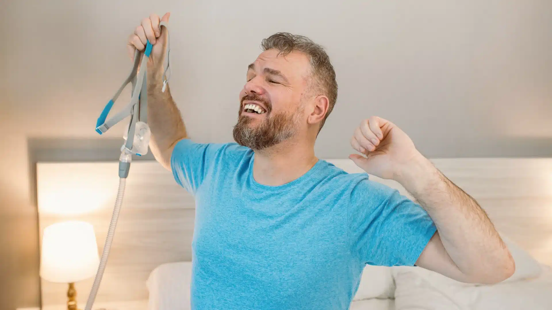 Happy man waking up refreshed after using CPAP machine for sleep apnea treatment