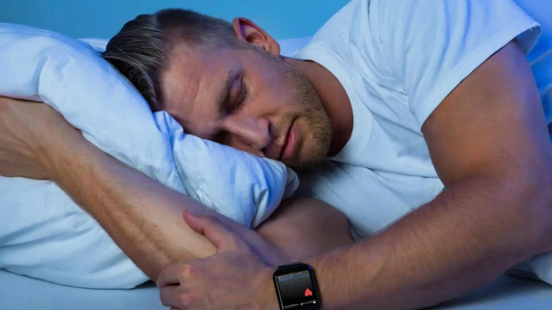Man sleeping with smartwatch tracking heart rate and sleep patterns