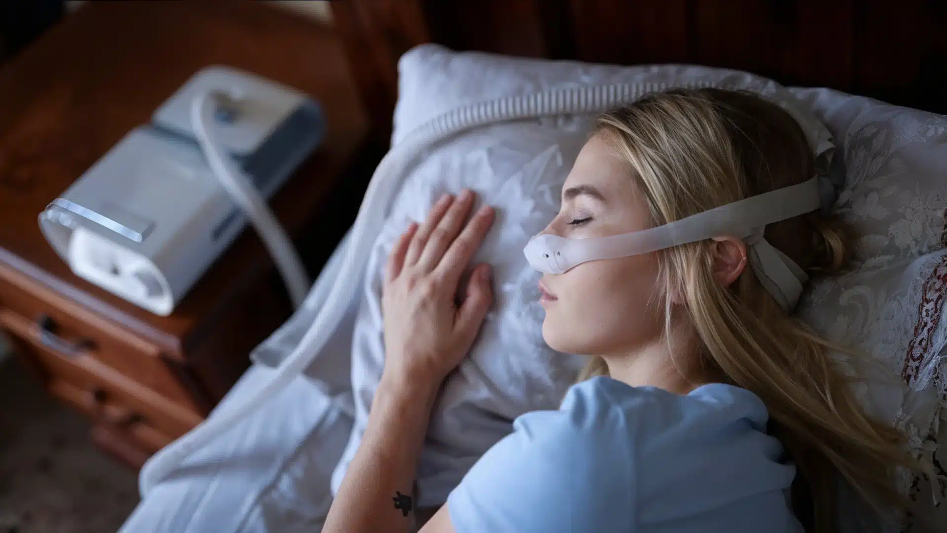 Woman sleeping with CPAP nasal mask for sleep apnea treatment at home