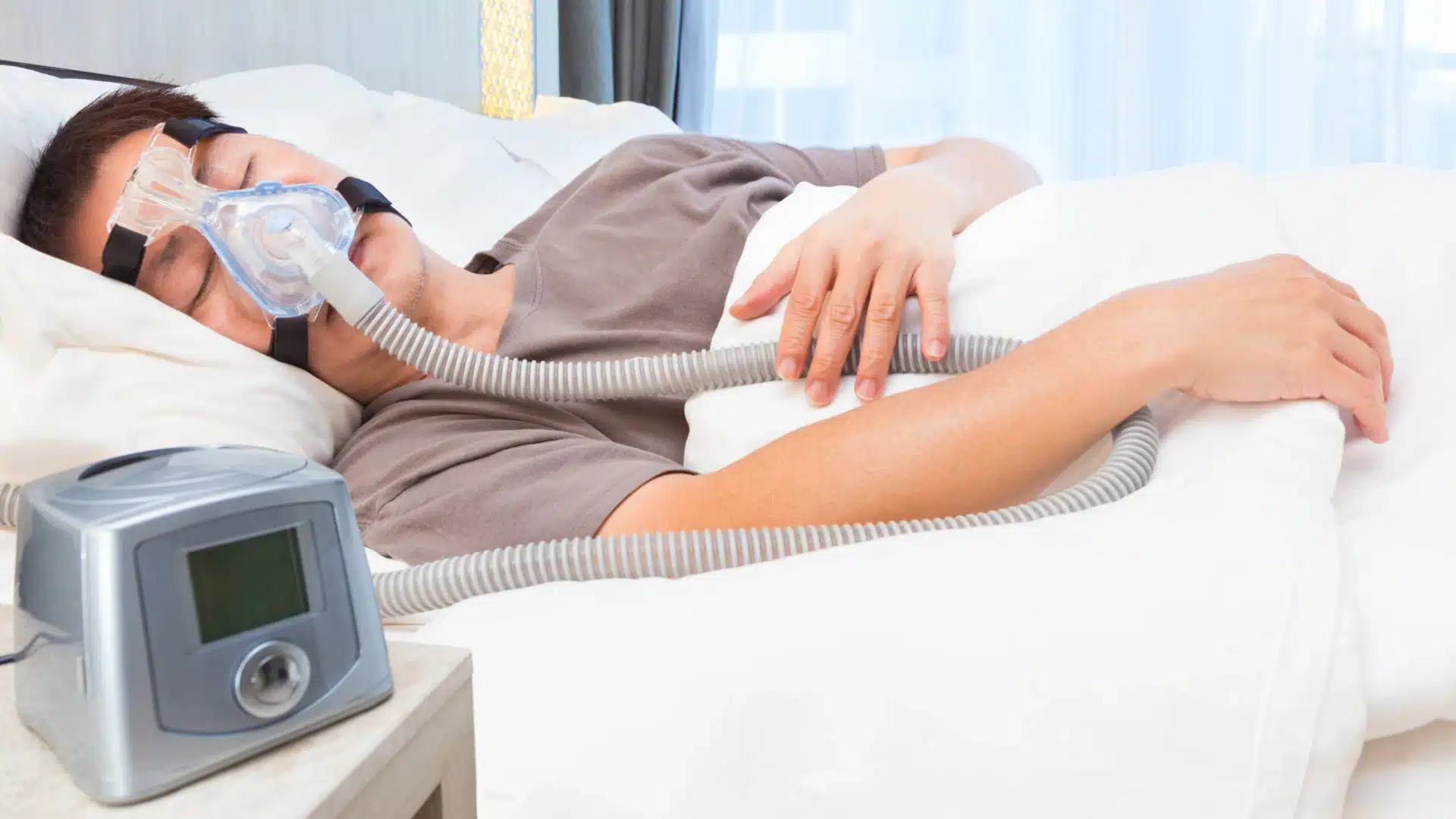 Man sleeping with CPAP machine and face mask for sleep apnea treatment